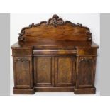 A VICTORIAN MAHOGANY SIDEBOARD, the serpentine back with floral carving, the break-front top above