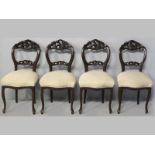 A SET OF FOUR MAHOGANY DINING CHAIRS, the hooped backs with heavily carved cresting and splats,