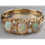 AN 18CT YELLOW GOLD, OPAL AND WHITE SAPPHIRE RING, with three oval opals, interspaced by four