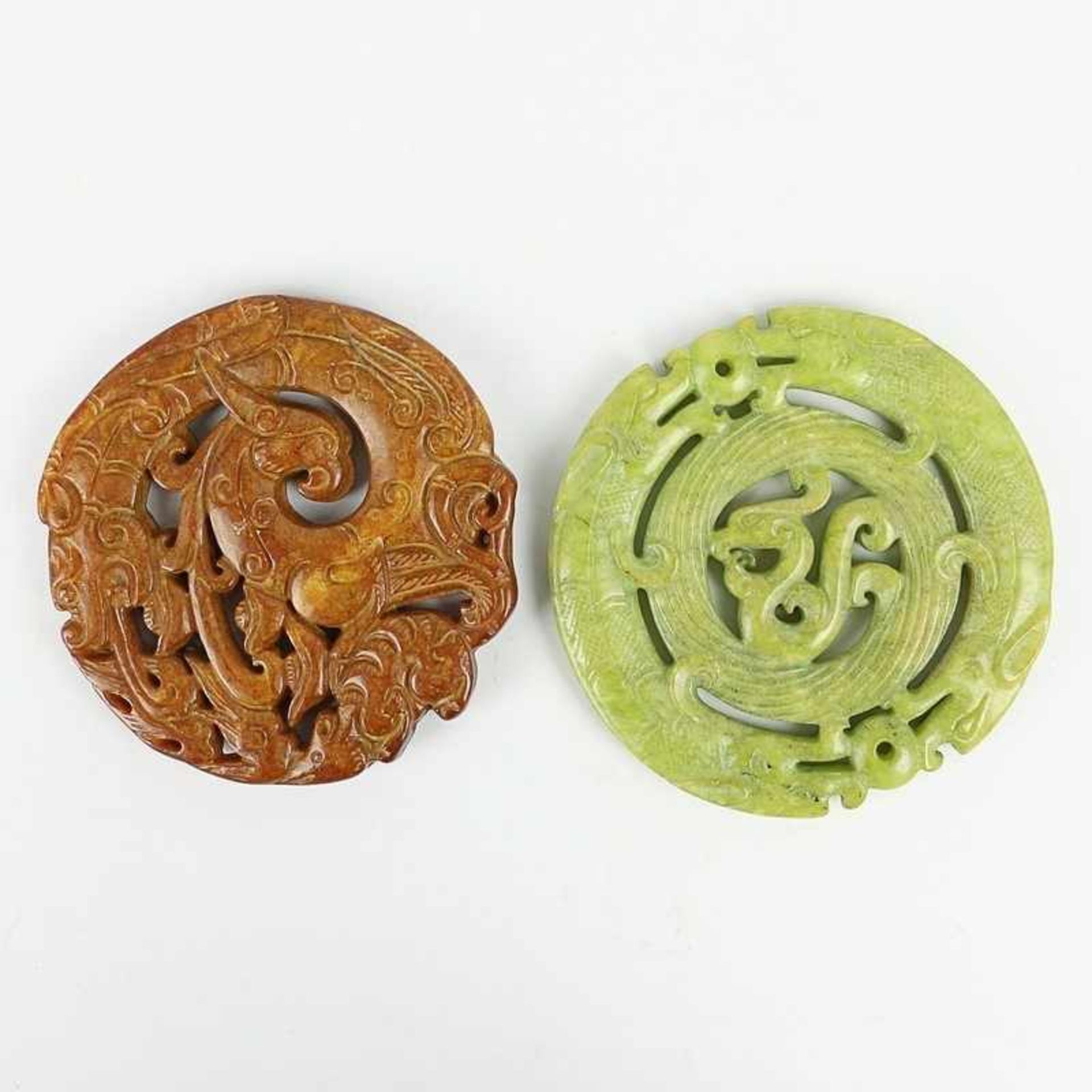 Paar Bi-Scheiben 20.Jh., China, geschnitzter Stein, grün- u. braunfarben, Fabeltiere, min.