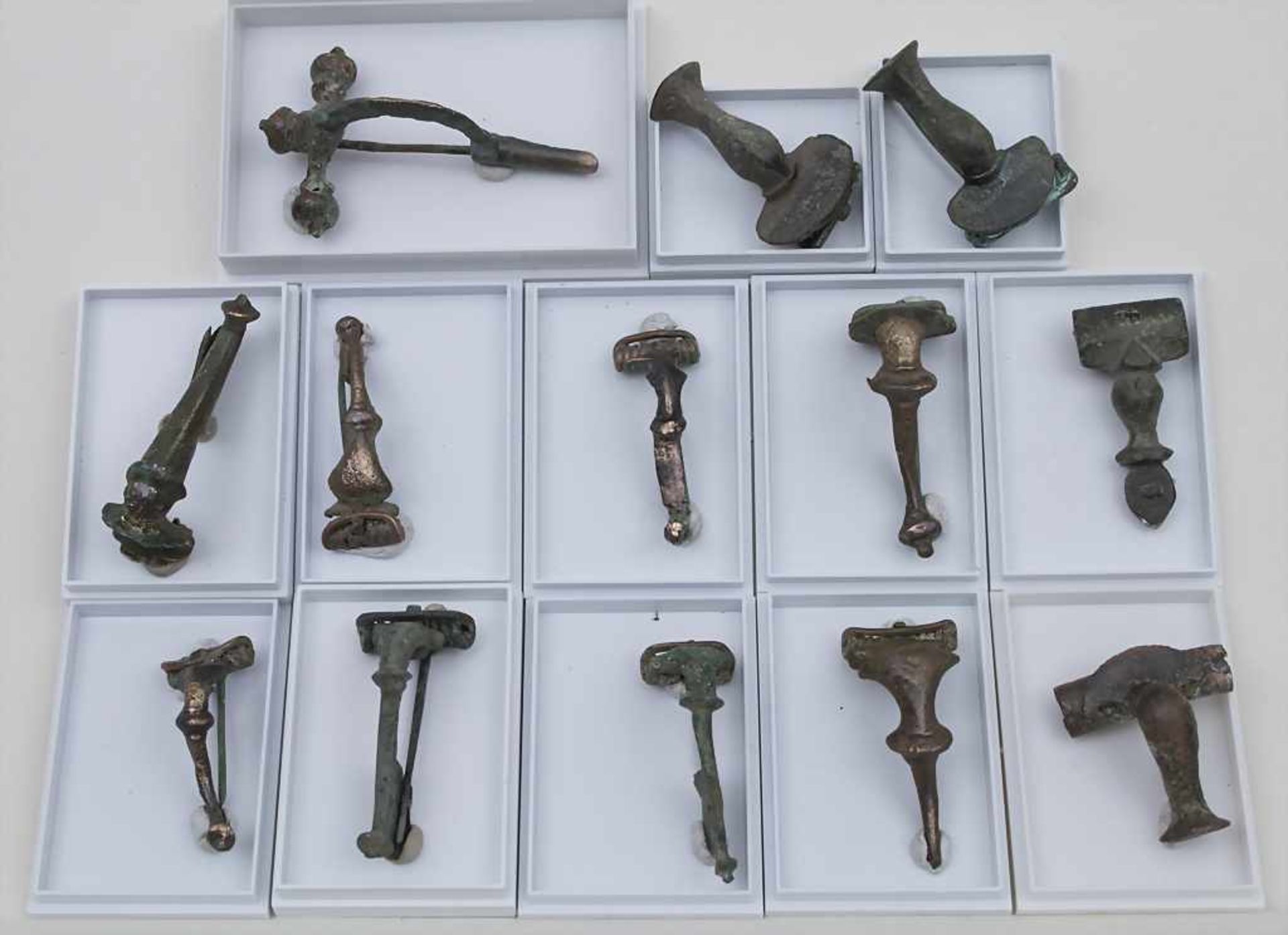 Lot 13 römische Bronzefibeln / 13 Roman Bronze Fibulae darunter 9 Trompetenfibeln, 2 Kniefibeln, 1