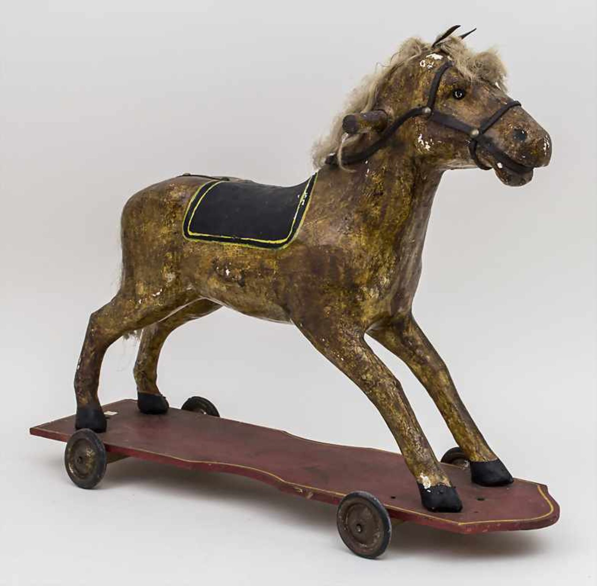 Spielzeugpferd auf Rollen / A toy horse on wheels, um 1900 Material: farbig gefasst, auf Platte
