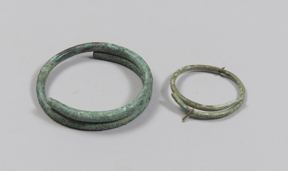 TWO ETRUSCAN BRONZE ARMILLS, 8TH-6TH CENTURY B.C. Rod with a smooth circular section that wraps