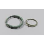 TWO ETRUSCAN BRONZE ARMILLS, 8TH-6TH CENTURY B.C. Rod with a smooth circular section that wraps