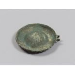 BRONZE LID, 6TH-4TH CENTURY B.C. Disc profile molded with a central recess, decorated on the