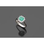 RING in white gold 18 kts., to outline of flower with central emerald and contour of diamonds.