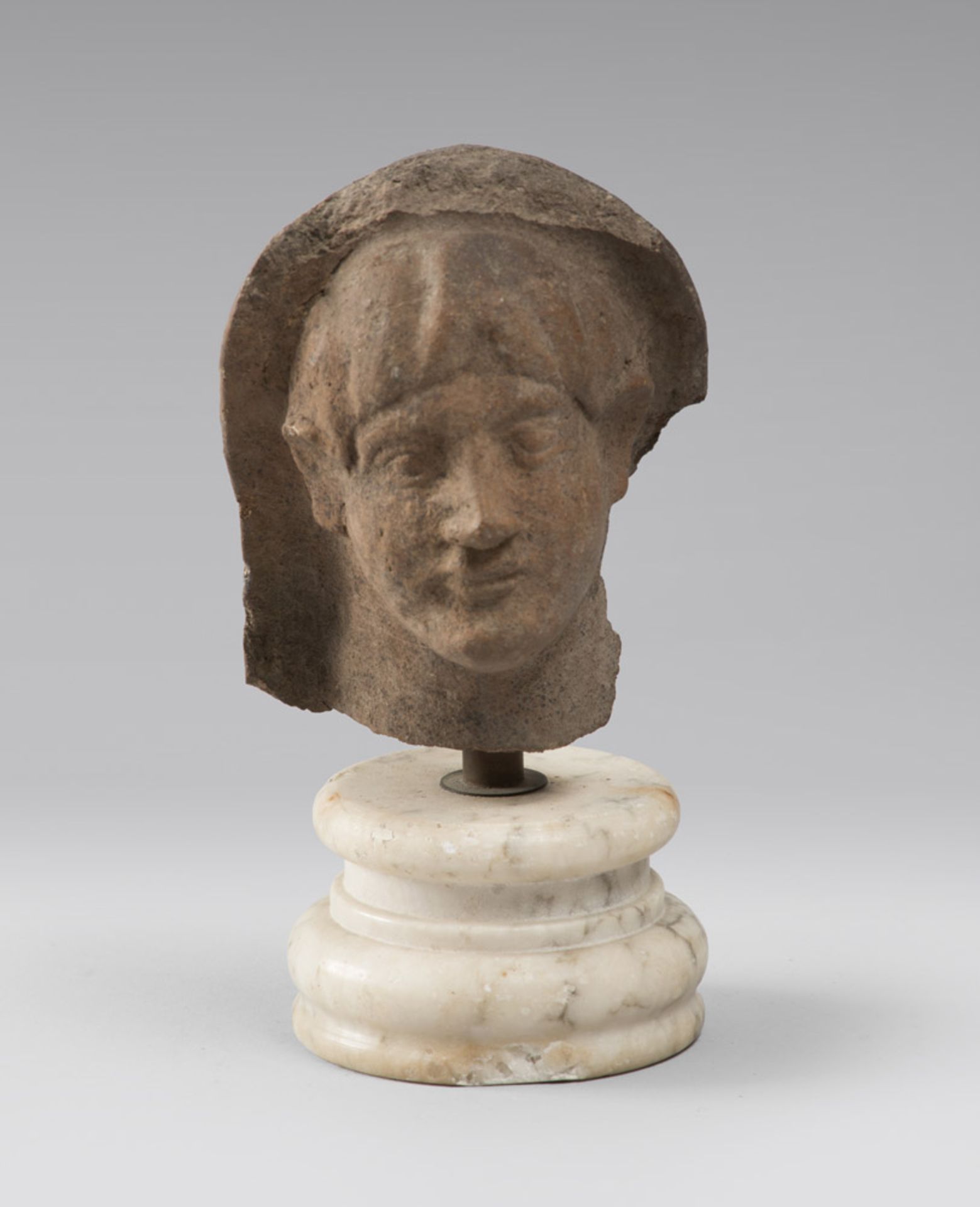 A VOTIVE MALE HEAD, 4TH, 1ST CENTURY B.C. Brown earthenware. Oval face, well-defined eyes, very