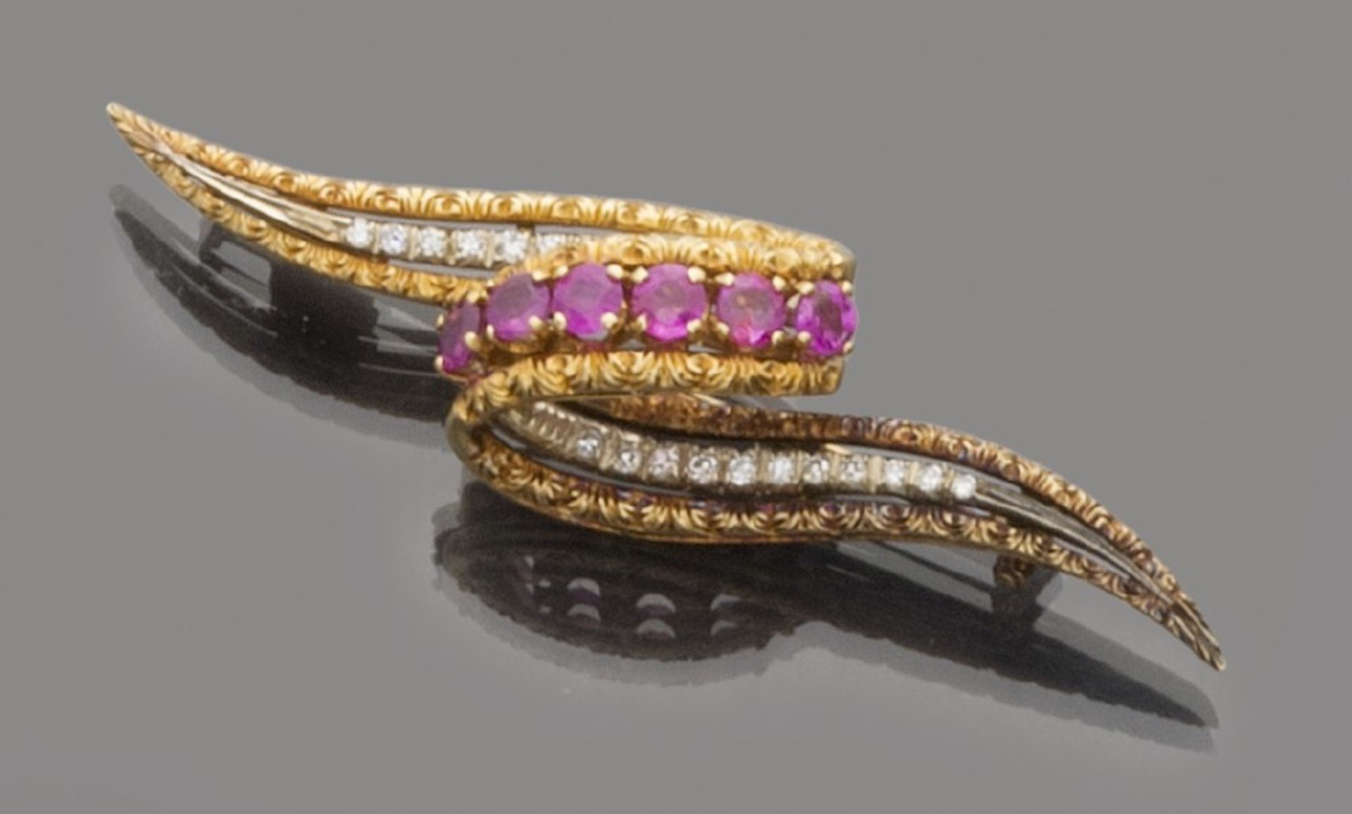 BROOCH in 18 kt yellow gold, with an abstract shape with the decoration of rubies and diamonds.