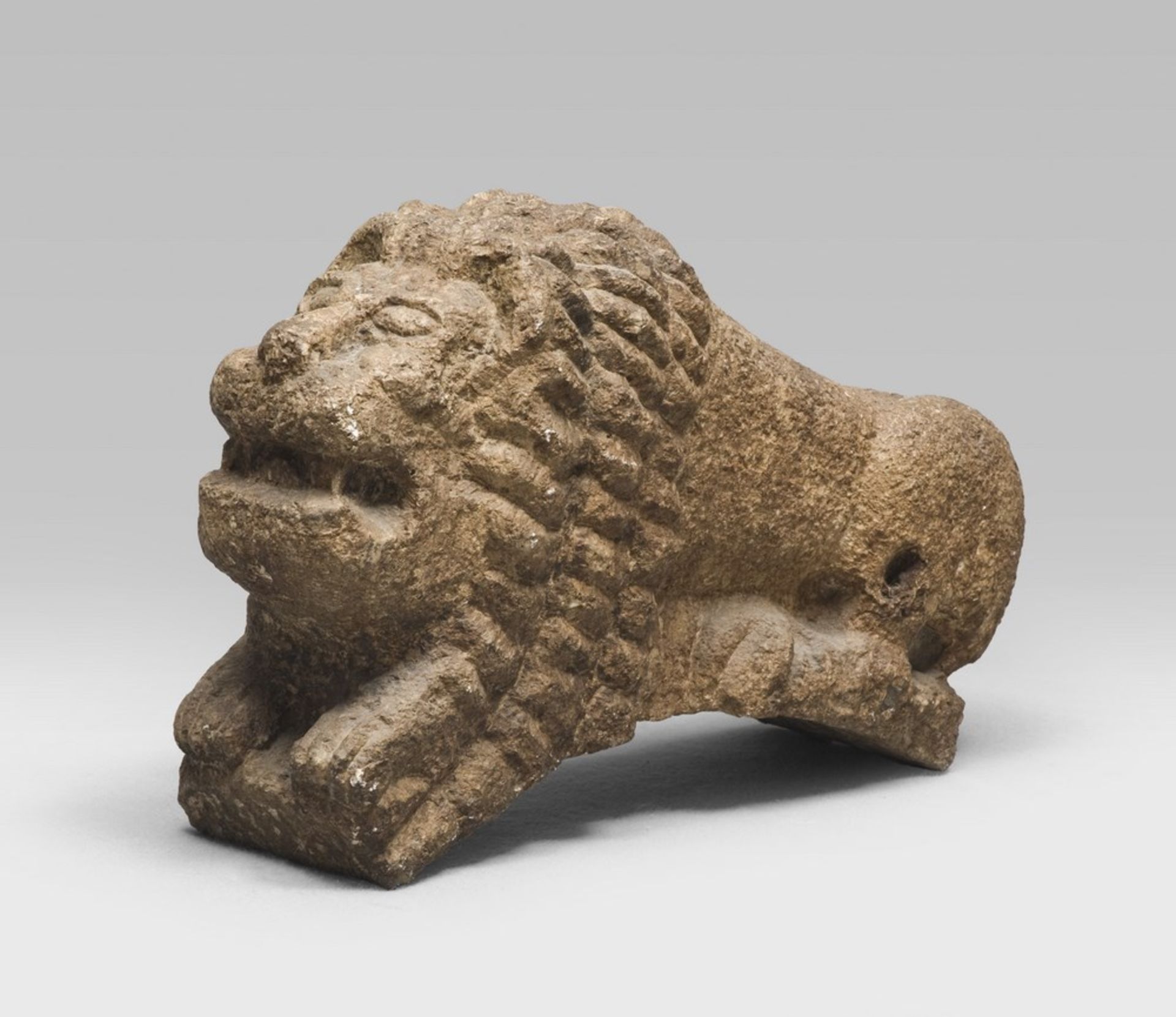 LION COLUMN-HOLDER SCULPTURE, 15TH CENTURY entirely in carved stone. The figure is squatting with