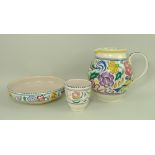 A Poole Pottery jug, bowl and beaker, decorated with flowers between mauve and green bands,