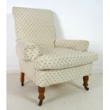 A late Victorian armchair, with turned front legs and castors, scroll arms and squared back,
