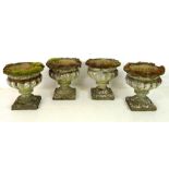 A set of four reconstituted stone garden urns, with lobed bodies, on integral square bases,
