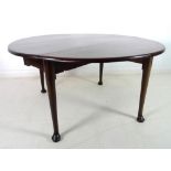 An early Georgian mahogany circular drop leaf dining table, with turned legs and pad feet,