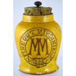 SHOP DISPLAY TOBACCO JAR. 10.5ins tall to top of cork lid with brass finial, mustard glaze with