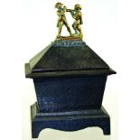 CAST IRON TOBACCO JAR. 6.75ins tall to top of cover with brass boxing figures, finial, sarcophagus