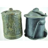 LEAD TOBACCO JARS. One with pipes in relief to lid & sides. One with men sat at table drinking (