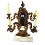 A gilt metal framed mirror, with four scrolling candle branches, on a rectangular white marble base,