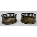 A pair of Sterling silver mounted bottle coasters, with pierced decoration within beaded rims,