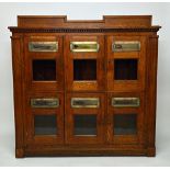 An early 20th century oak municipal post box with six glazed letter boxes, on plinth base,