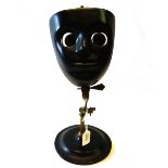 An optician's ebonised brass face mask with adjustable eye glass holders on an adjustable stand and