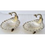 A pair of silver sweetmeat dishes, each of scallop shell form, raised on three dolphin shaped feet,