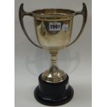 A silver twin handled trophy cup of baluster form, presentation inscribed, on a black plinth,