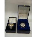 A modern silver cased music box of circular form,