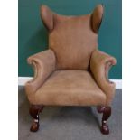 A late Victorian shaped suede upholstered wingback chair on claw and ball feet,