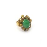 A gold ring, claw set with an oval cabochon jade, within a foliate surround, detailed 18 K,