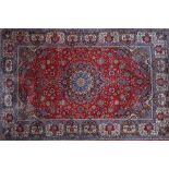 A Kashan carpet, Persian, the madder field with a bold indigo and black medallion,