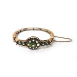 A Russian gold and peridot oval hinged bangle, in a split bar design, on a snap clasp,