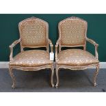A pair of parcel gilt and white painted Louis XV style fauteuils, 103cm high x 70cm wide.
