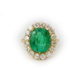 A gold, emerald and diamond cluster ring, claw set with the oval cut emerald at the centre,