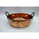A large Victorian circular copper preserve pan with brass side handles, 56cm across.