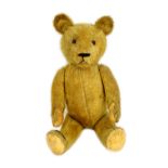 A Steiff style teddy bear, early 20th century, with golden fur and jointed limbs, 63cm.