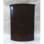 A George III mahogany boxwood strung bowfronted wall hanging corner cabinet,