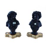 A pair of patinated bronze busts, 20th century, each cast as a semi-naked female on a socle,