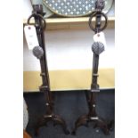 A pair of heavy steel fire dogs with ring finial and foliate cast decoration against a fluted shaft