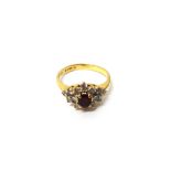 An 18ct gold, ruby and diamond set cluster ring, claw set with the oval cut ruby at the centre,