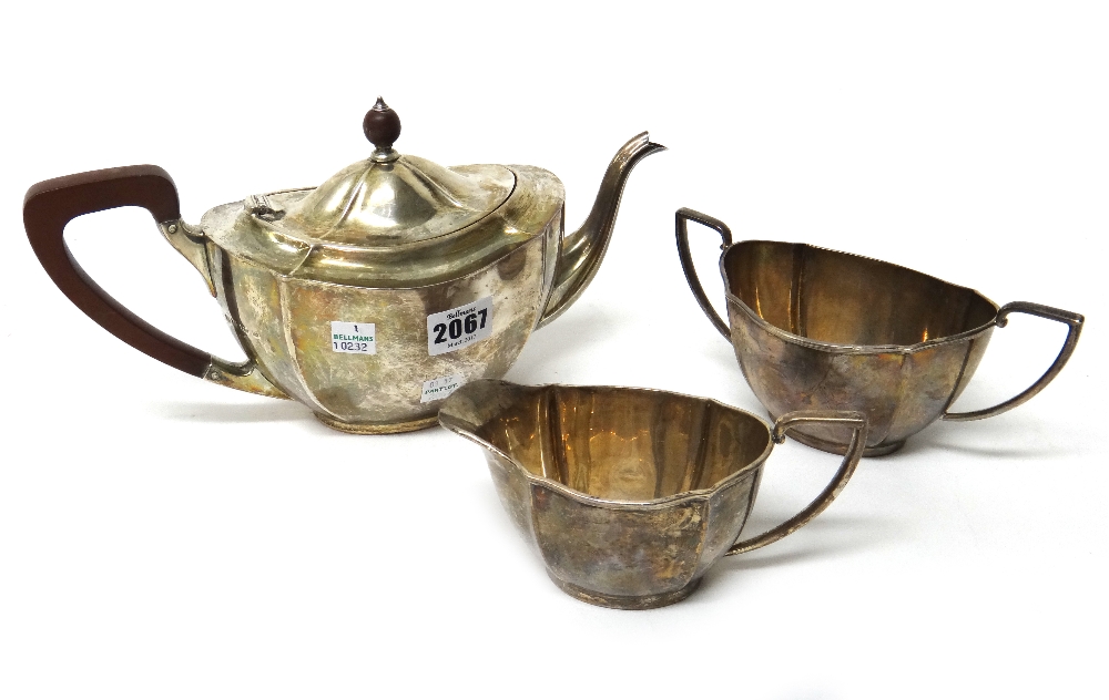 A silver three piece tea set, of shaped oval panelled form, comprising; a teapot,