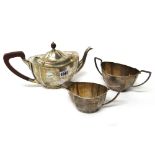 A silver three piece tea set, of shaped oval panelled form, comprising; a teapot,