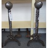 A pair of heavy steel fire dogs, with beaten spherical finial and barleytwist shaft,
