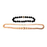 A single row necklace of black onyx beads, on a diamond set circular clasp,