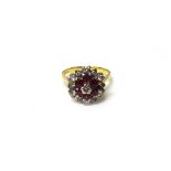 A gold, diamond and ruby cluster ring, claw set with the circular cut diamond at the centre,