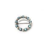 A 9ct white gold, blue zircon and cultured pearl set circular brooch,