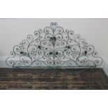 A wrought iron bed head, 20th century, of scrolling form with stems, leaves and flower heads,