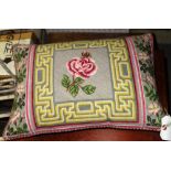 A needlework cushion with rose decoration.