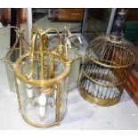 A group of three gilt metal and glass hanging lanterns and a brass bird cage, (4).