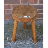 A milking stool with octagonal elm top on three staked ash supports, 38cm high.