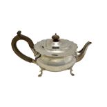 A silver teapot, of squat circular form having a shaped rim, raised on four pad feet,